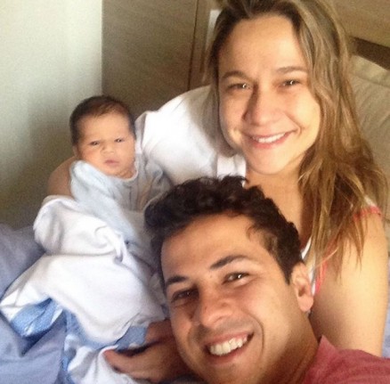 Fernanda Gentil e Matheus Braga sorriem ao lado do filho Gabriel, o primeiro do casal