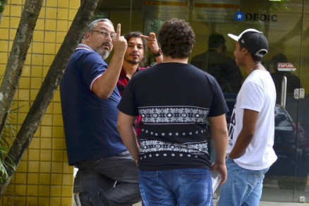 Douglas Sampaio e o pai, Adilson, mostram o dedo para o fotgrafo em frente a delegacia no Rio