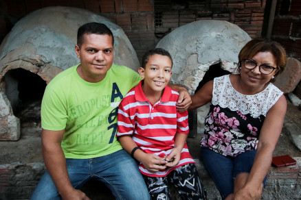 Rivelton Campos, o filho Lucas e a sua me, Evanil Campos, em frente aos fornos de barro usados para preparar a iguaria