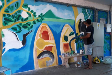 O artista e professor Wender Carlos pinta painel em escola
