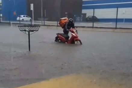 Um entregador precisou empurrar sua moto pela rua alagada