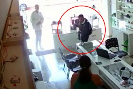 Momento em que ladro aponta arma para a vendedora