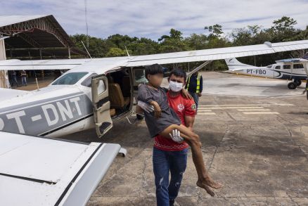Mulher yanomami com malaria  carregada no colo por tcnico de enfermagem ao desembarcar 