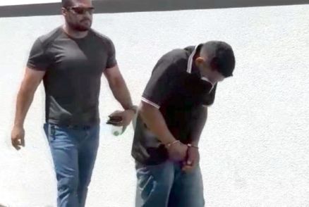 O suspeito sendo conduzido por um policial militar 