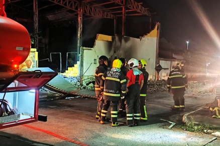 Homens do Corpo de Bombeiros e a fbrica destruda aos fundos