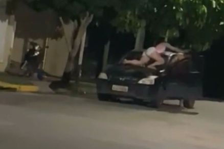 Mulher sobre o cap e o para-brisa do carro aps briga de casal