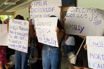 Famlia de adolescente segurando cartazes durante protesto realizado em velrio
