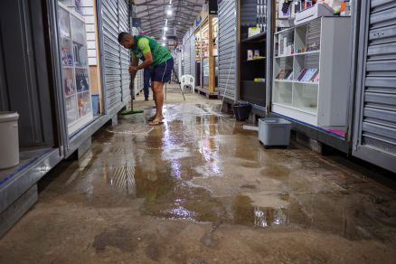 Comerciante usando rodo para tirar o resto de �gua da chuva que inundou centro comercial 