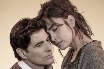 Homem e mulher com os olhos fechados, encostando as testas em gesto de proximidade. Homem veste camisa social branca com suter marrom, mulher usa blusa cinza e cardigan. Fundo neutro bege. Reynaldo Gianecchini e Maria Casadevall estrelam 'Um Dia Muito Esp