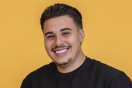 Homem jovem de cabelo curto e escuro sorri para a c�mera, vestindo camiseta preta e cal�a bege, com as m�os nos bolsos, em fundo amarelo liso. Pedro, que desistiu do BBB 26 ap�s importunar Jordana, sua colega de confinamento