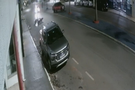 Momento em que motociclista bate em carro estacionado na via